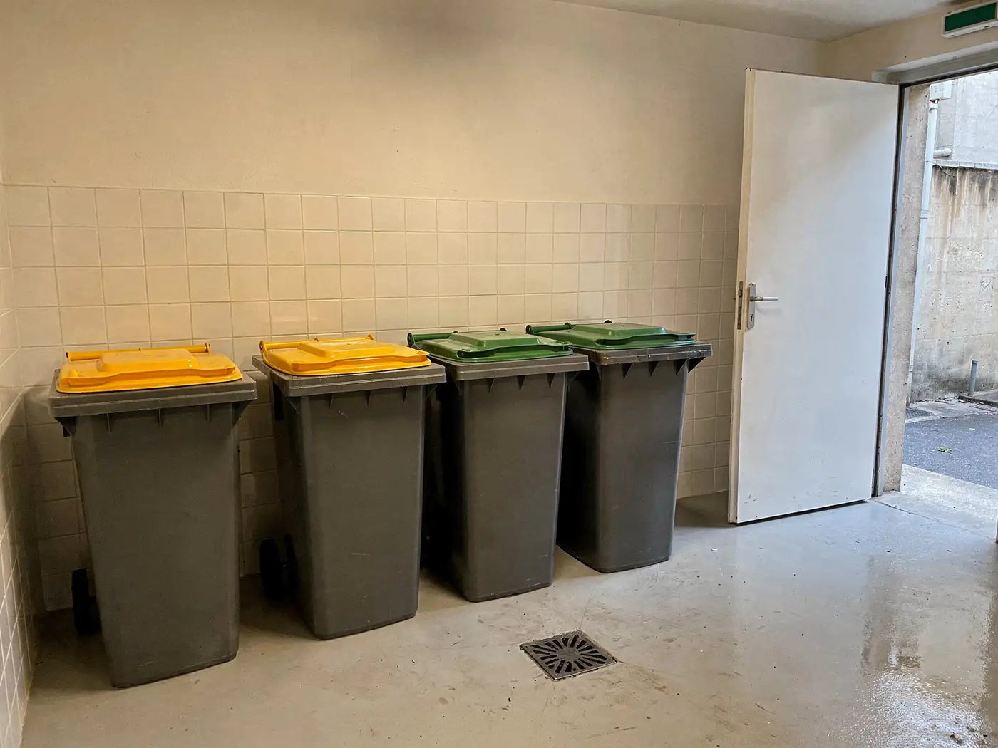 Local poubelles propre d'une copropriété à Lyon, bacs alignés et sol lavé